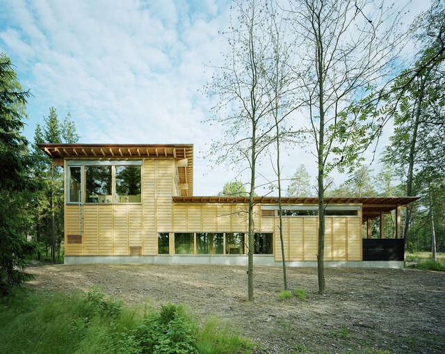 Light wooden building in the middle of a forest.