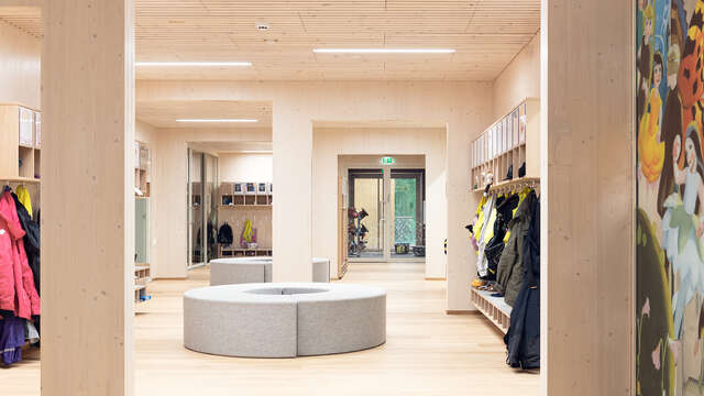 Kuva päiväkodin sisältä. Kuvassa on eteinen, jonka naulakoihin on ripustettu takkeja.