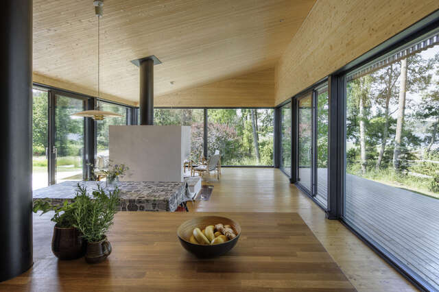 Interior of a space with glazed walls on three sides and a wooden floor and ceiling