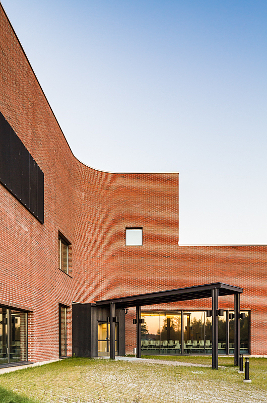 Red brick building, multiple windows and canopy to the entrance