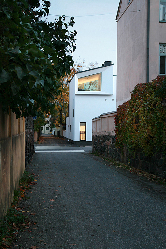 White detached house on an alley behind a rosa apartment house