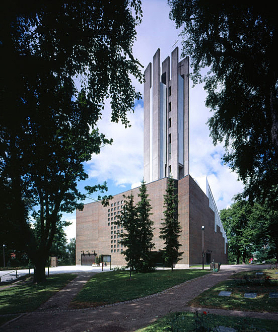 Red brick church with a glass detail at the front and a massive bell tower of raw concrete, integrated into the northwest corner of the church.