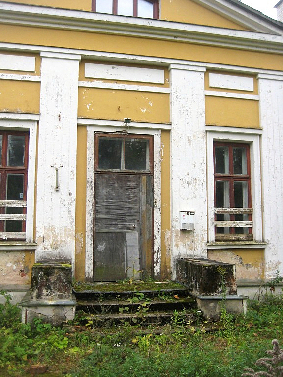 Old door in very bad condition with a overgrown garden around it.