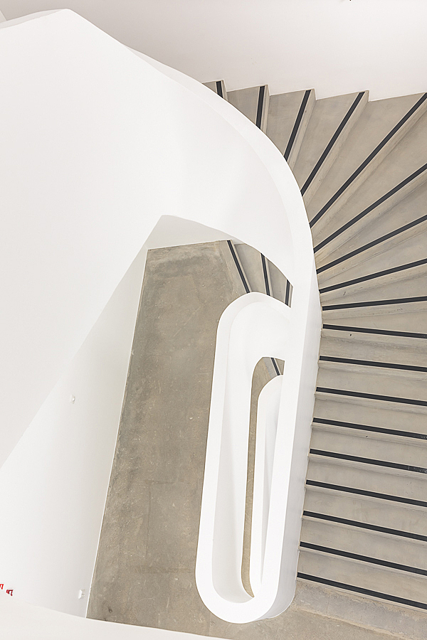 COncrete staircase with white railing and wall.