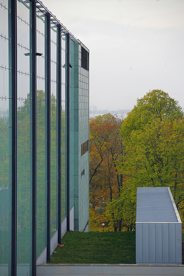 Autumnal trees behind the building and its glass wall.
