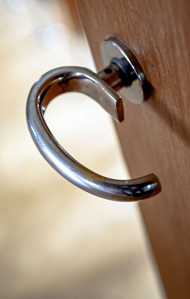 A round metallic door handle attached to s wooden door.