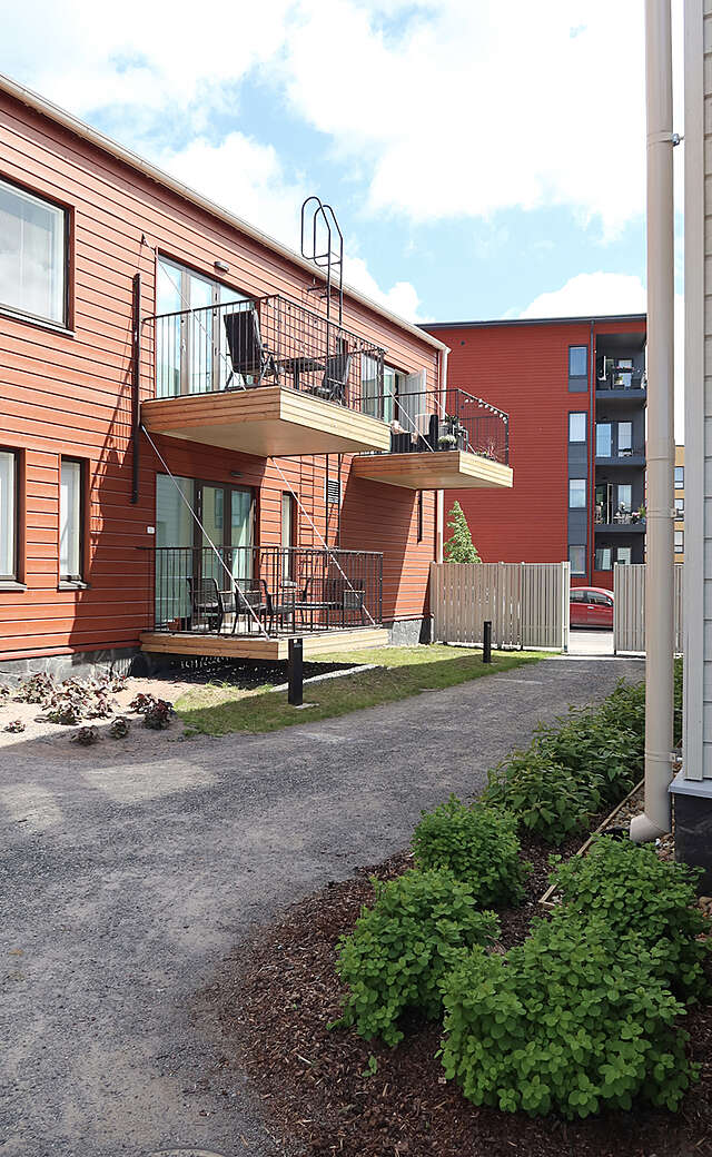 Red, two-storey block of flats with large, open balconies.