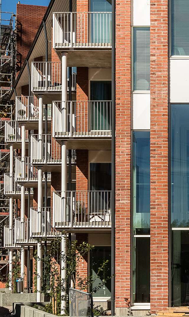 Red-Brick building with large glass windows, balconies with white railings.