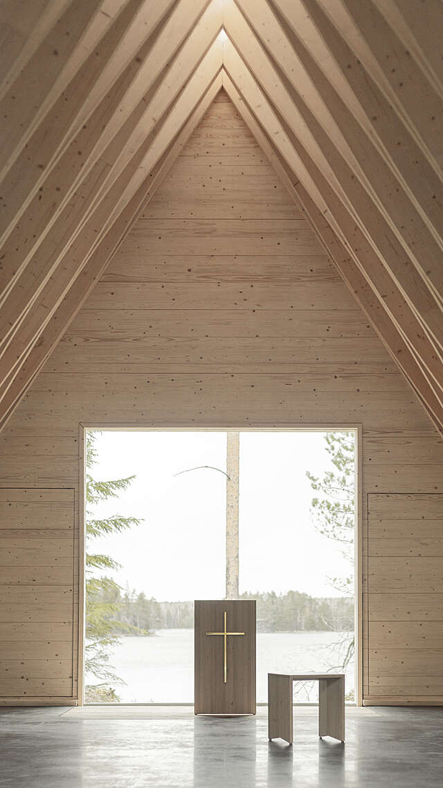 Interior of a wooden, pitched-roofed chapel, looking towards the altar standing in front of a large windoe