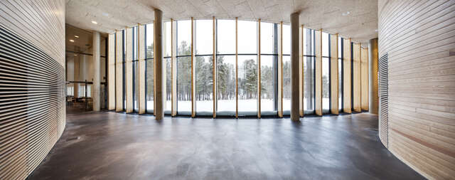 Large glass wall divided with wooden vertical planks. Snowy trees visible behind the wall.