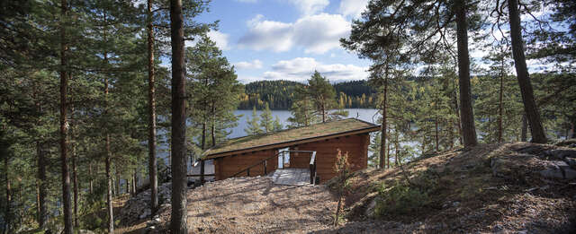 Wooden sauna in the forest and next to a lake.