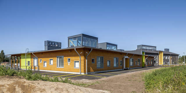 Yellow wooden facade with lime green details and many windows.