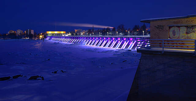 Night view of a dam lit up in blue and purple