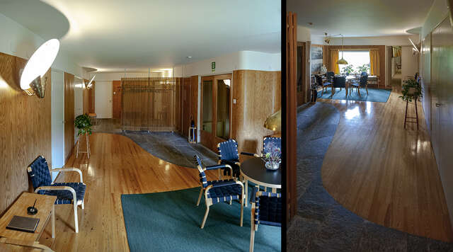 The elegant interior architecture of a living room that has wooden flooring and doors. The walls are white with some parts decorated with wooden panels. The floor also has a stone decoration near the entrance. The furniture consists of wooden table and chairs designed by Artek. The walls and the roof create a curved form that is repeated in the floor where the border between the stone and the wood flooring makes a curved form.
