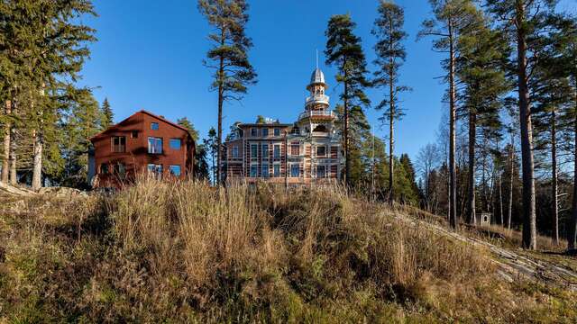 Two large wooden buikdings side by side. Left one is red and more modern, right one is a historical villa.