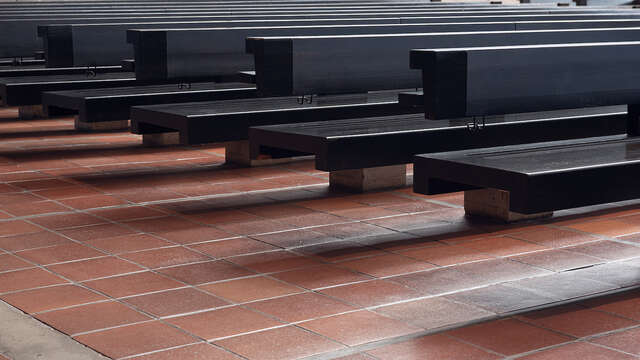 A paved brick floor with rows of black benches