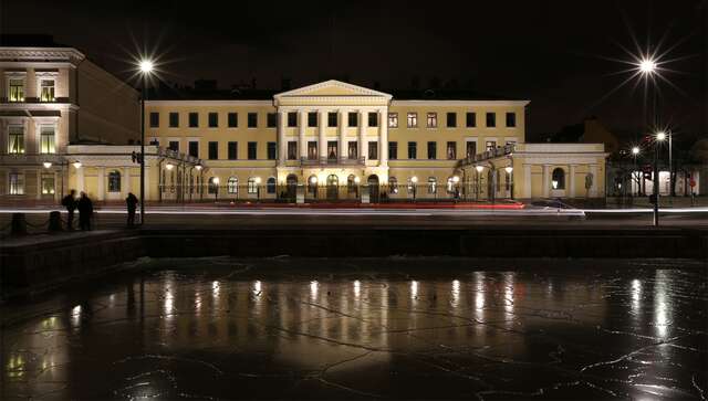 Yellow building with arch doorways and decorative pillars at night.