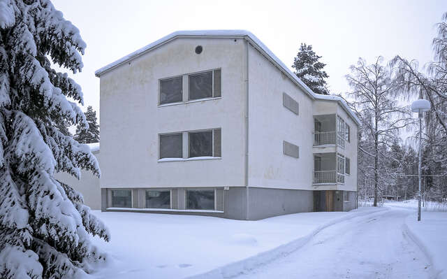 A two-storey house with white plastered walls and a pitched roof.
