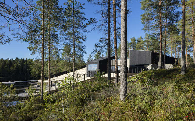Dark wooden structures with nature in foreground.