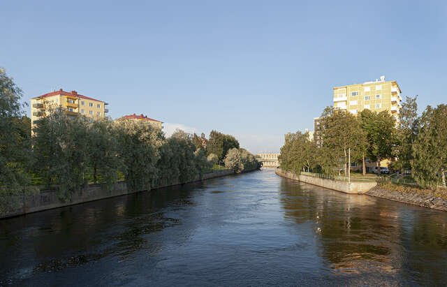 Photo taken over the river leading towards the power plant. The powerplant shows on the background of the photo, bathing in sunlight.