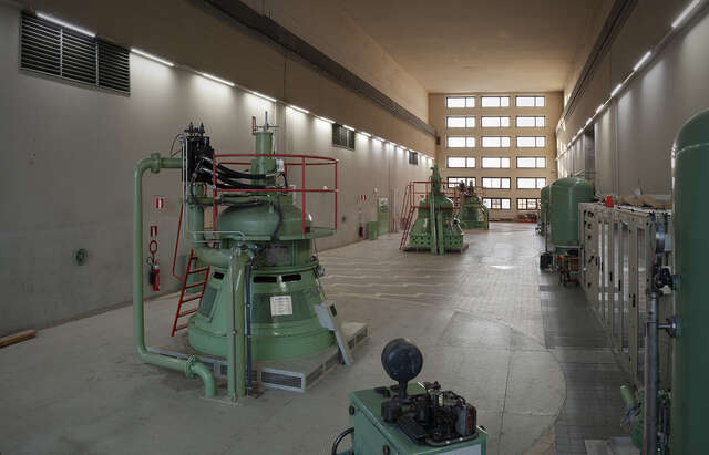 Photo of a room with machinery painted bright green, with windows on the background that let the natural light in.