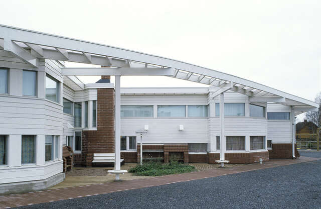 Facade with a red-brick foundation and white wood panels at the top.