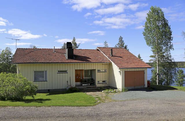Picture of a wooden, yellow residential cottage-like house in the summer.