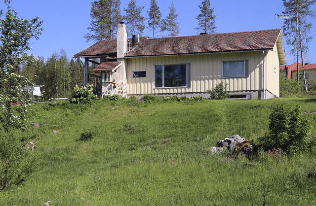 Picture of a wooden, yellow residential cottage-like house in the summer.