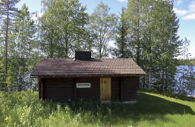Picture of a log-built dark wooden residential cottage in the summer.