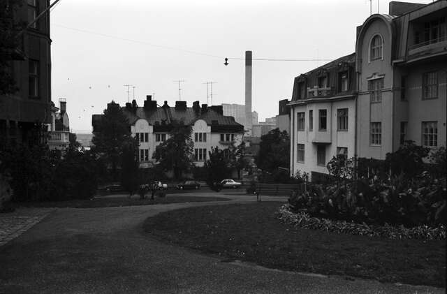 Black and white picture of a public square with multiple storey buildings and villas around it.