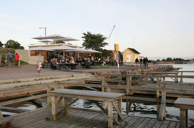 Wooden carpet washing tables and a seaside café in the background