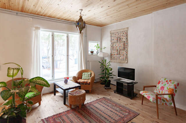 A Building's living room furnished with plants, different furniture and a television.