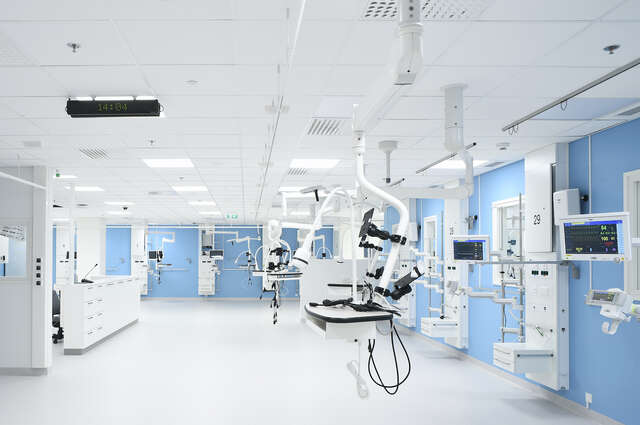 A large, mostly white room with hospital surgical robotic equipment.