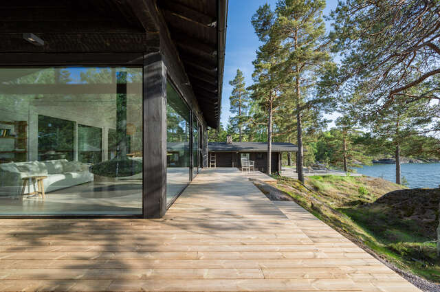 A large wooden deck outside of a cabin with large glass windows.