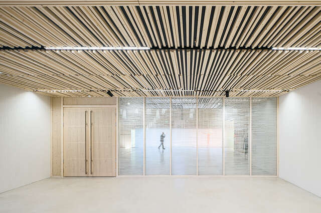 Light room with a profiled wood ceiling and doors and well as a textured glass wall.