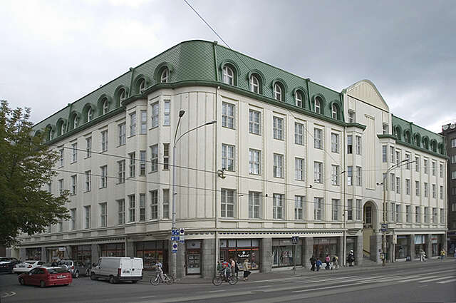 Old white multiple story building with stores at the bottom floor.