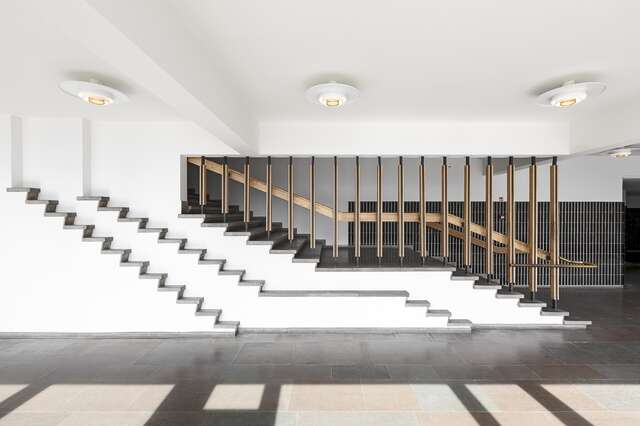 White interior with dark stairs and wooden railings.