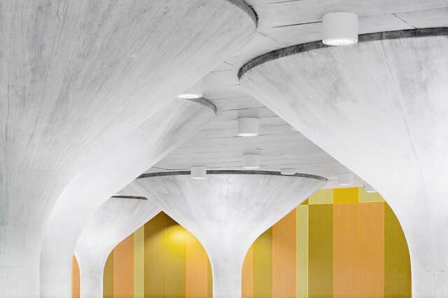 Mushroom shaped concrete pillars with a retro yellow orange and green colored wall in the background.