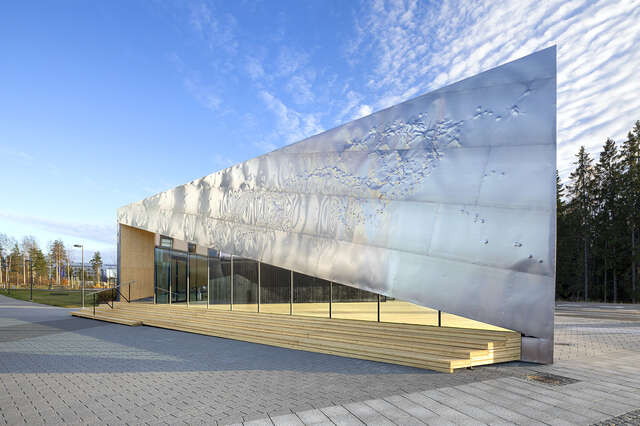 A large rectangular structure with a metal facade and large glass windows.