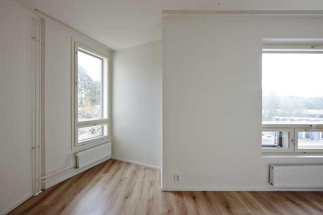 Empty room with white walls, wooden floors and a nook with window to the side.