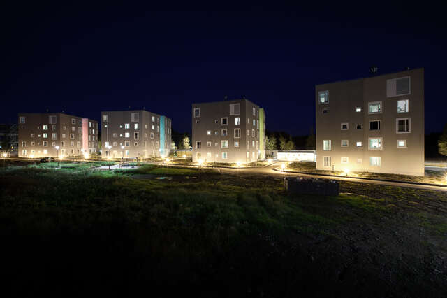 Four five-storey grey block of flats in evening light