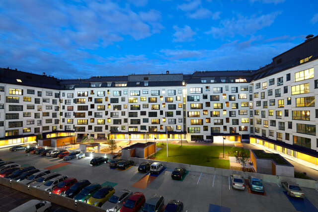White housing block with a parking area in the foreground
