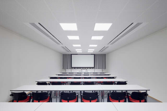 White auditorium with tables, chairs and a screen