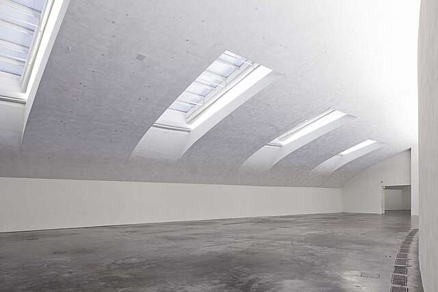 White room with a curved roof and ceiling windows.