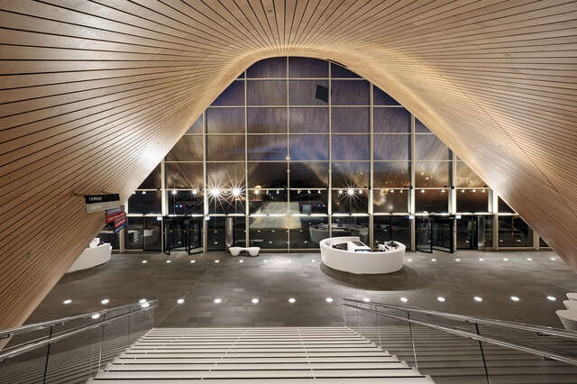 View from top of stairs towards a lobby with a parabol-shaped wooden ceiling