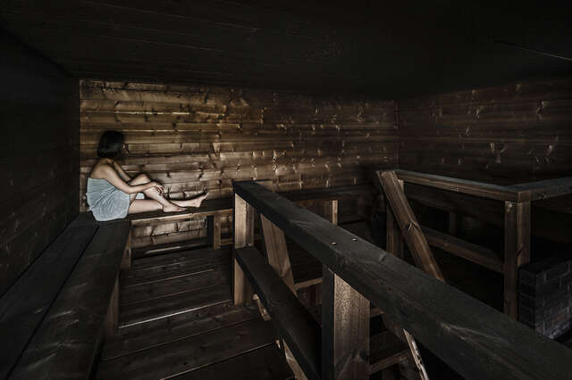 Woman sitting at the back of a dark sauna.