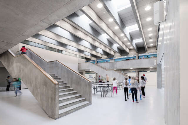 Spacious canteen in an light environment with concrete ceilings walls and stairs.