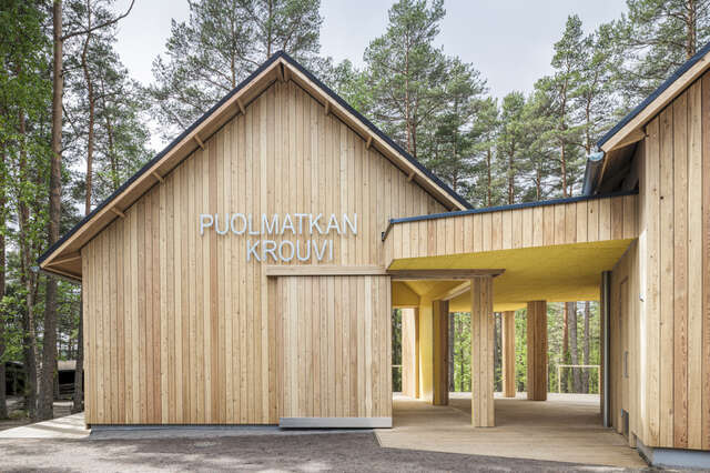 Closeup of two wood-coloured volumes joined by a canopy