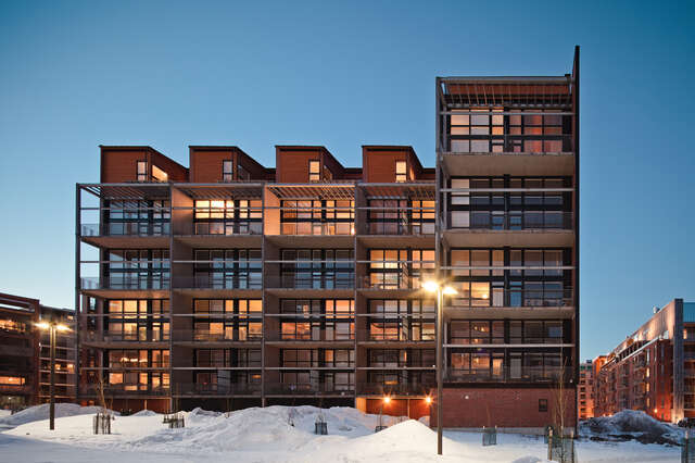 Multiple story apartment building with red bricks and large balconies.