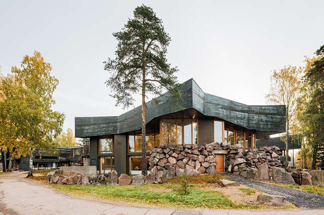 Ceiling with cliff-like eaves, copper and wood claddings and a massive boulder wall.